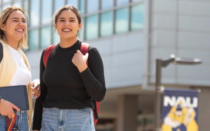 Dos estudiantes se paran afuera juntos en el campus de NAU.