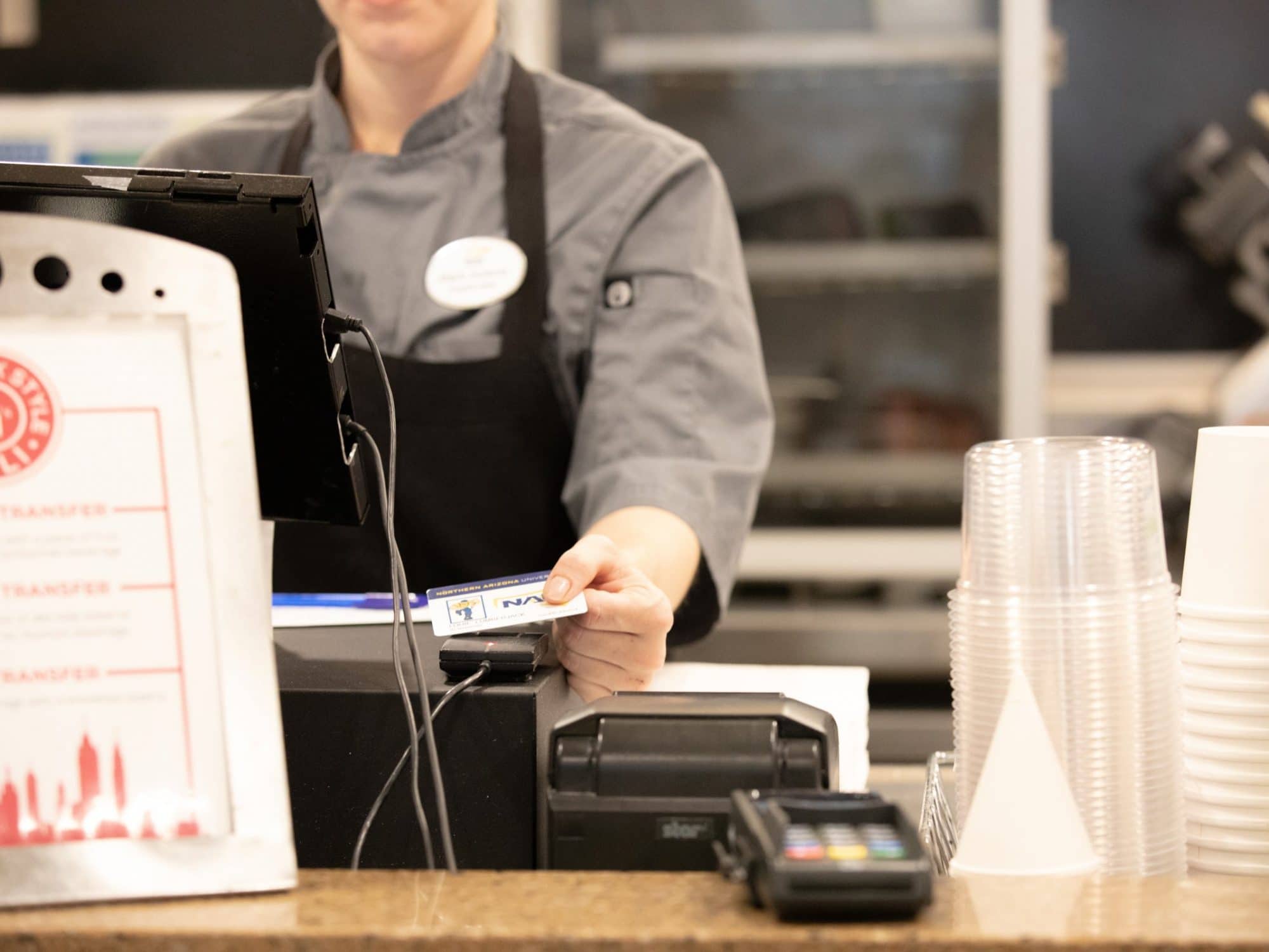 Un cajero devuelve una identificación de estudiante en un comedor de NAU después de marcar una comida.