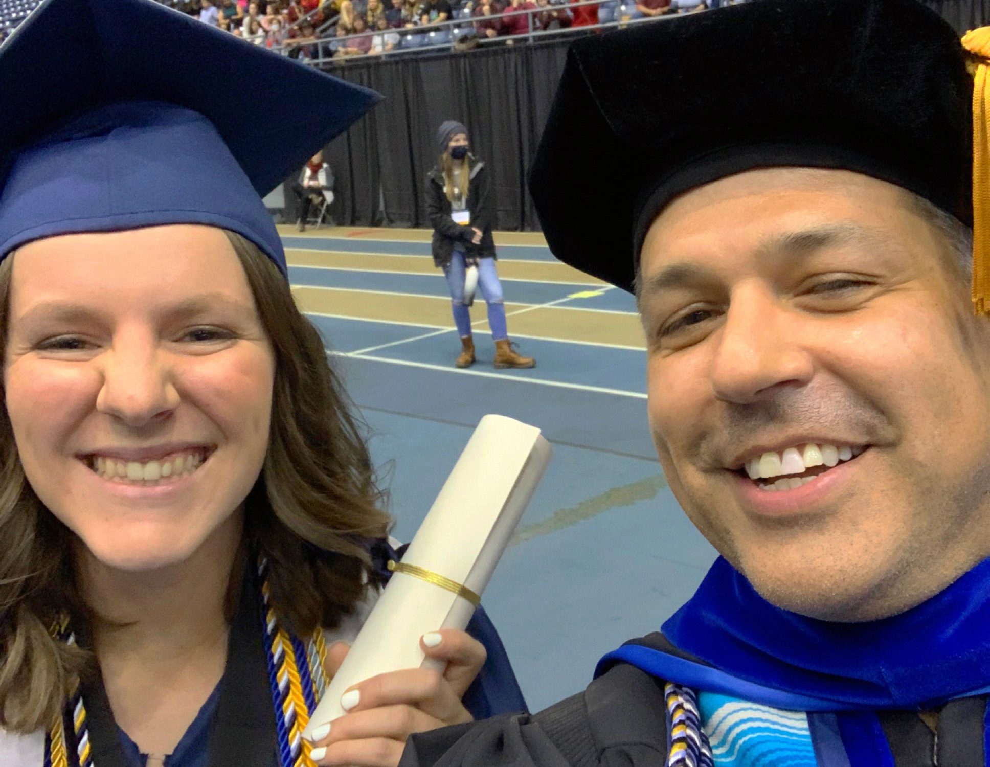 La nueva graduada Lizy Martínez y el profesor T. Mark Montoya se unen durante una ceremonia de graduación de NAU.