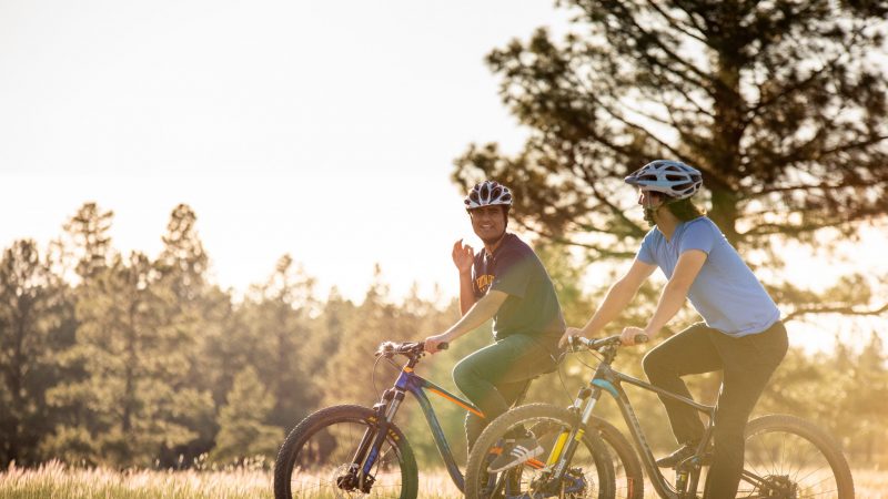 Dos personas andan en bicicletas y hablan en Flagstaff, parque de Arizona.