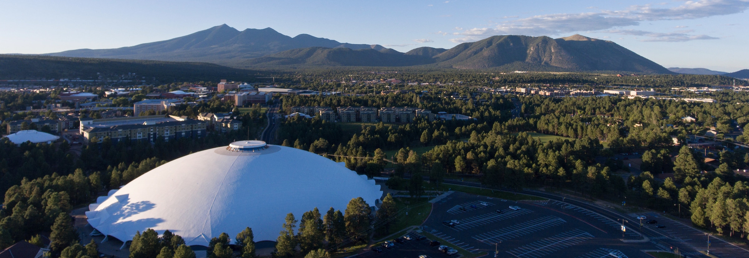 Aerial picture of NAU Skydome and campus taken from the air with the San Francisco Peak mountains in the background
