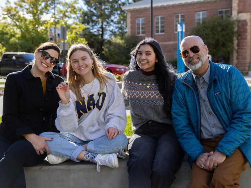 NAU student with her family sitting outside, smiling.