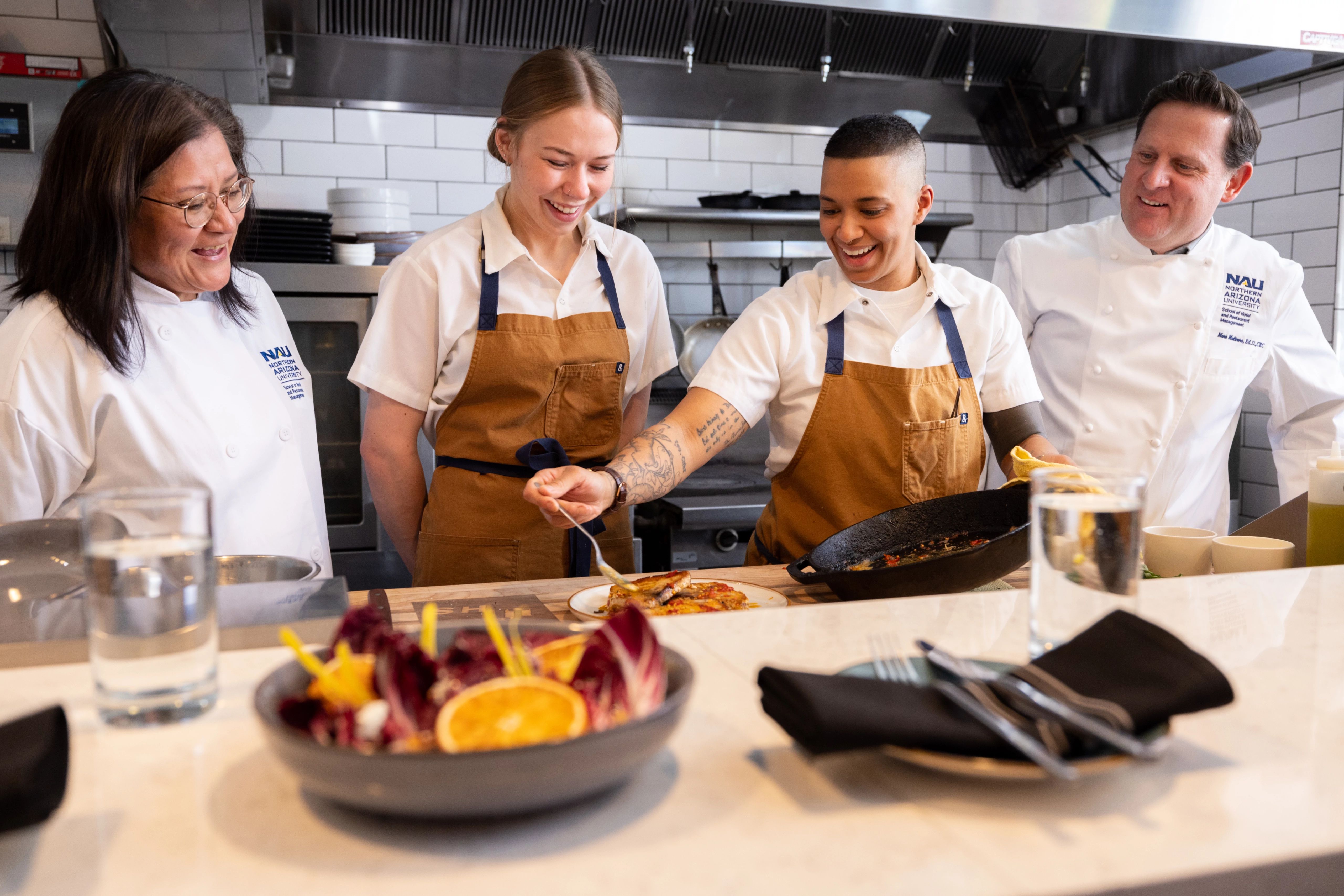 NAU Hotel and Restaurant Management students cooking in a kitchen with faculty members