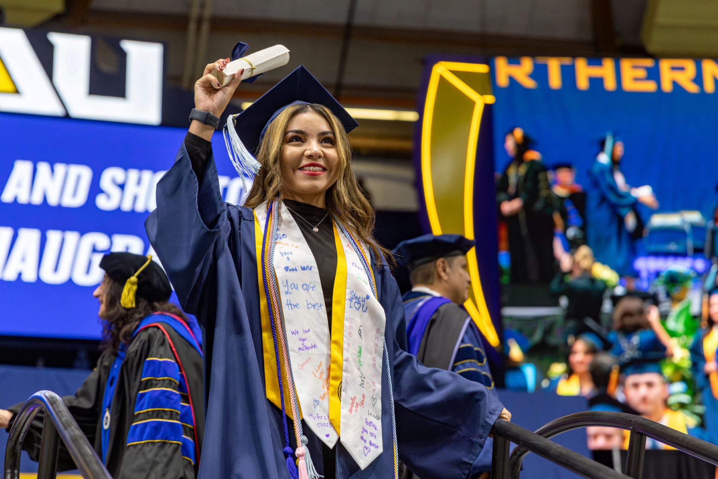 A student holds up their diploma at N A U commencement.