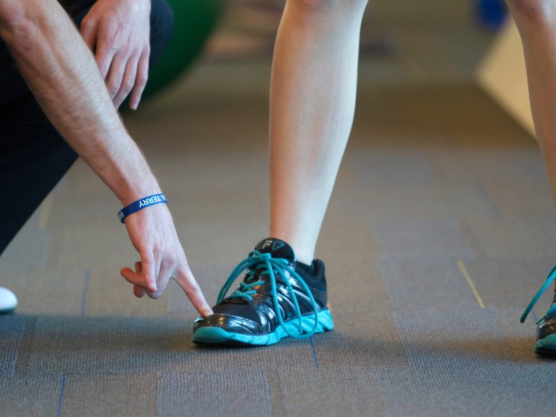 A trainer points to the tip of someone's shoe.
