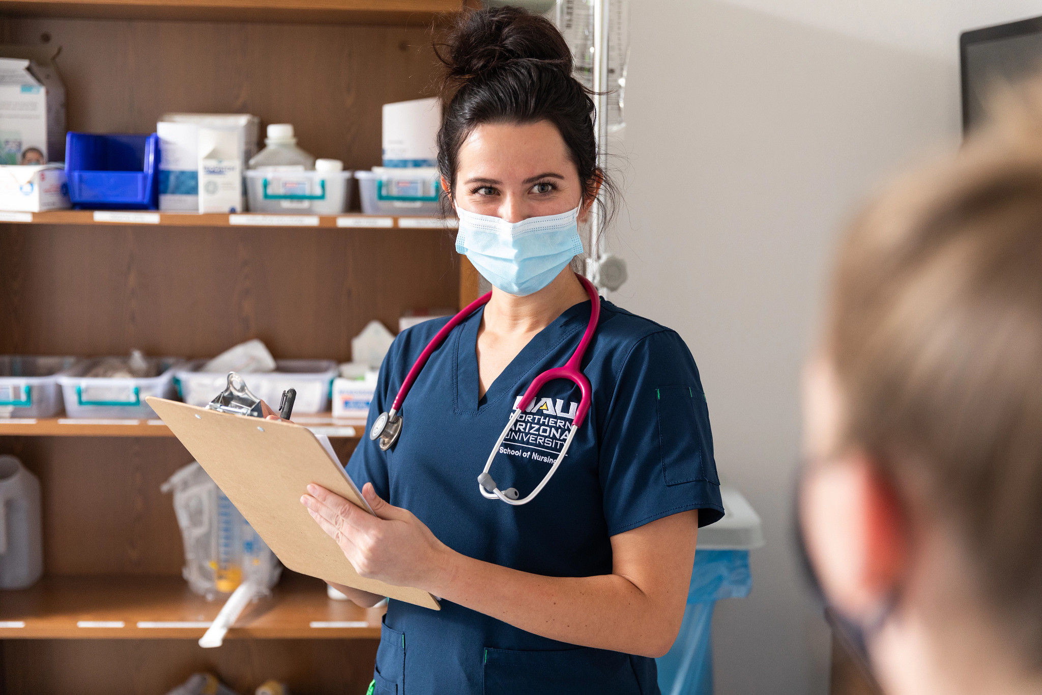 Nursing student talking to a patient and making notes.
