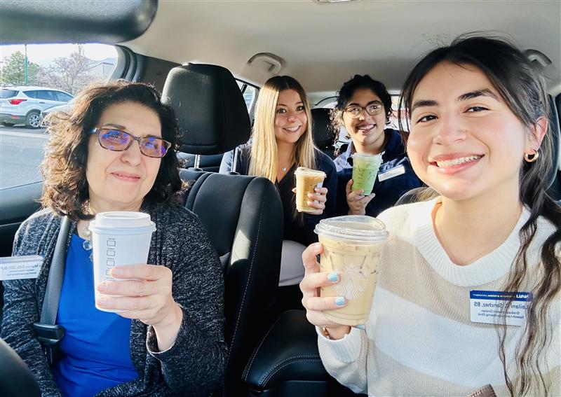 N A U Communication Sciences and Disorders students and professor Fe Murray holding coffee and smiling inside a vehicle.