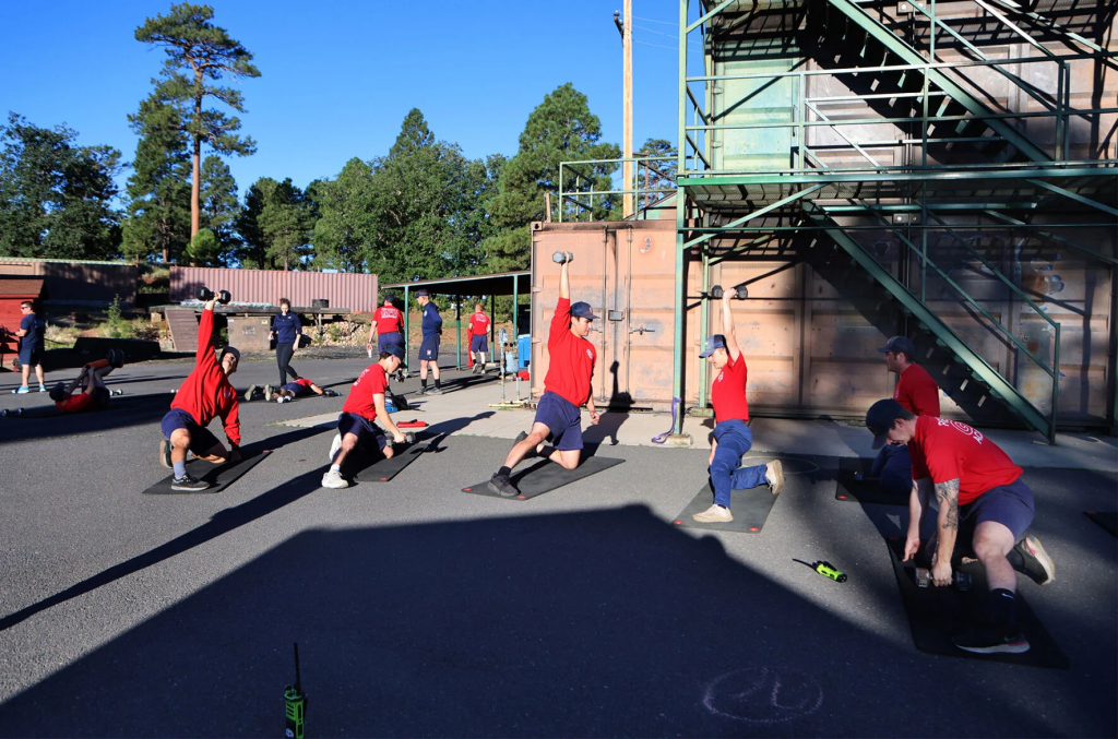 Firefighter academy recruits complete workouts during an athletic training session for a program launched by Northern Arizona University athletic training faculty member Megan Mulready at the Flagstaff Fire Department training tower.