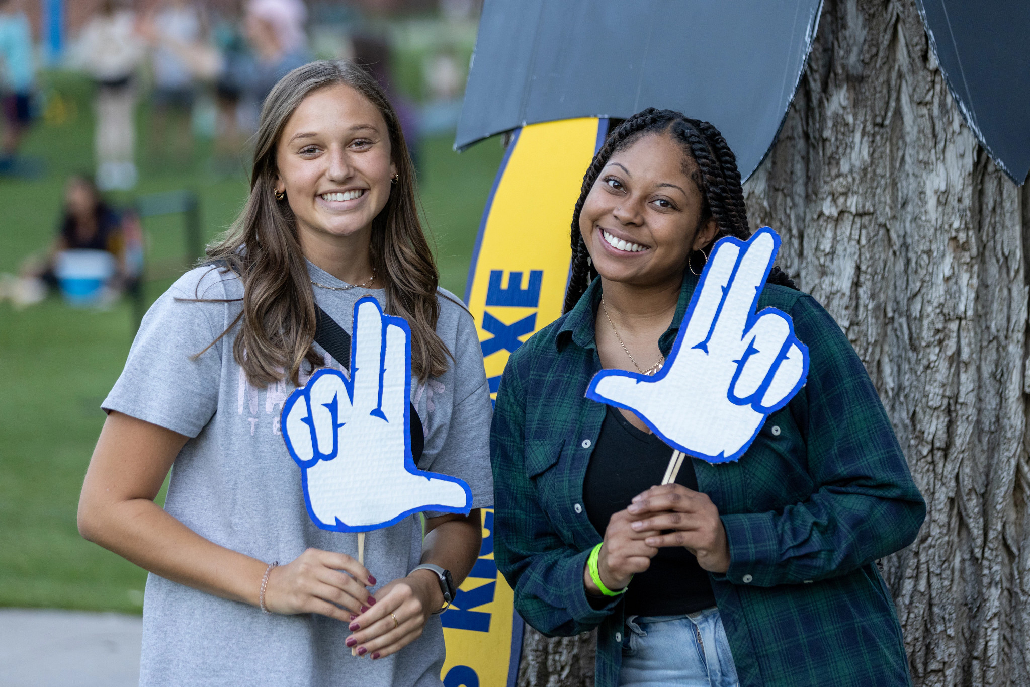 Students outdoors holding an axe up sign.
