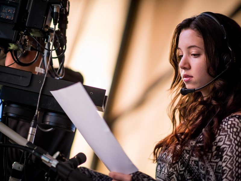 Student looking at script while operating production camera.