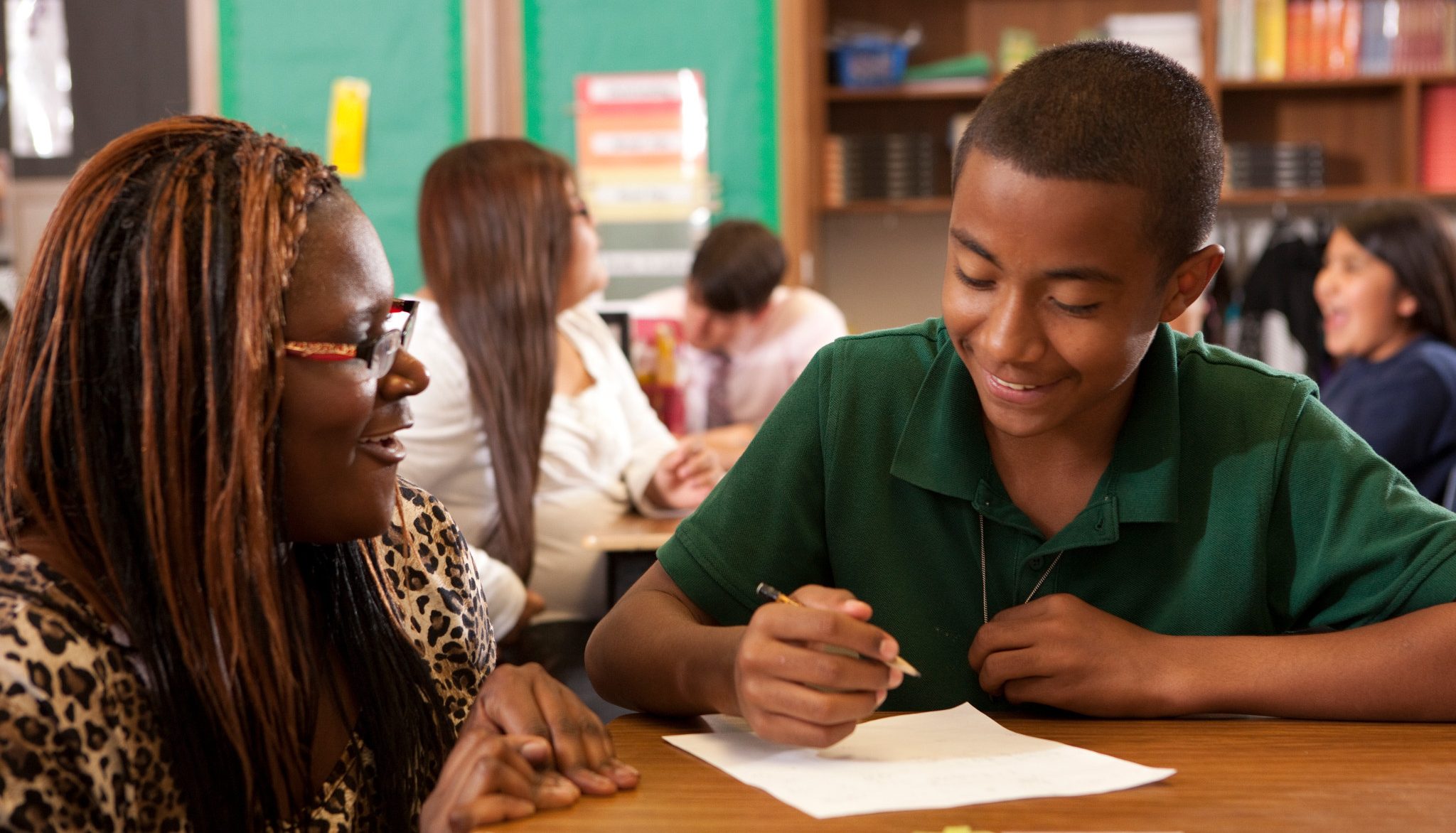 Student teacher helps student with writing assignment.