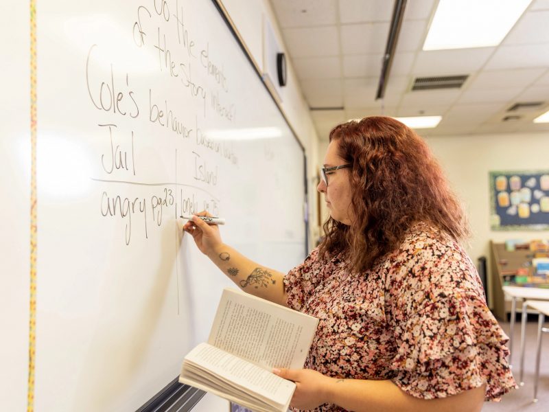 Student teacher writing on white board.