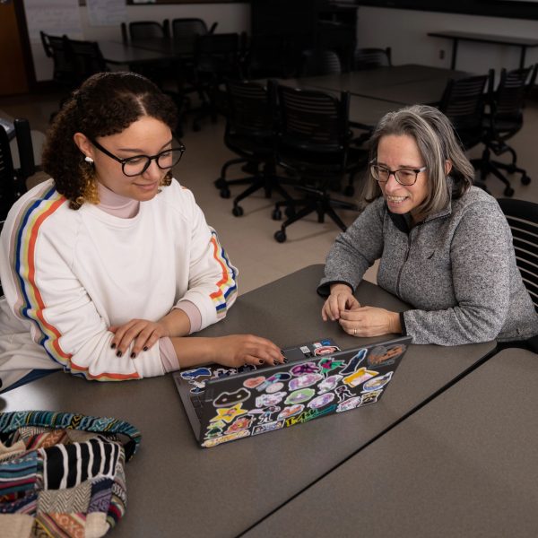 Professor helping student on laptop.