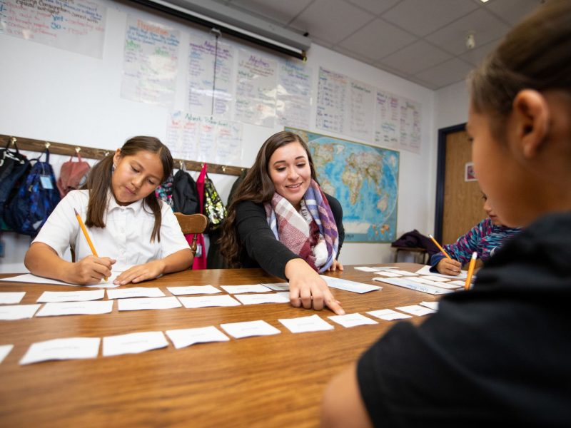 N A U student teacher helps child with assignment.
