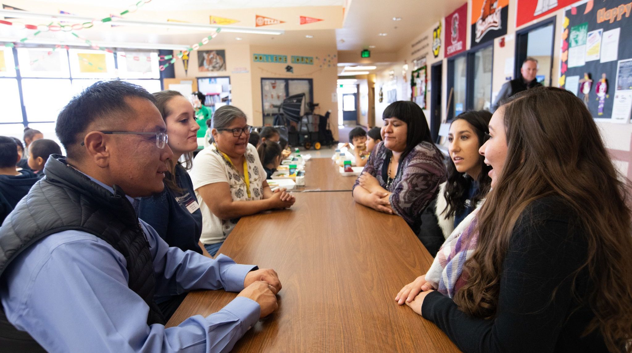 N A U student teacher speak with other teachers at school.