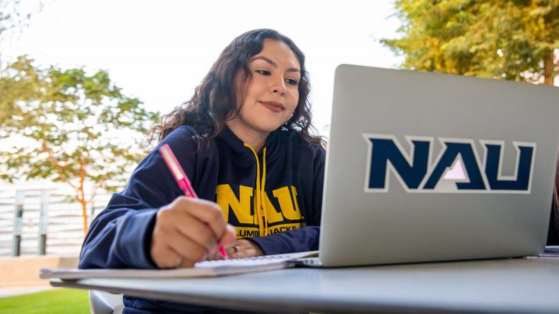 N A U student working outside on a laptop.