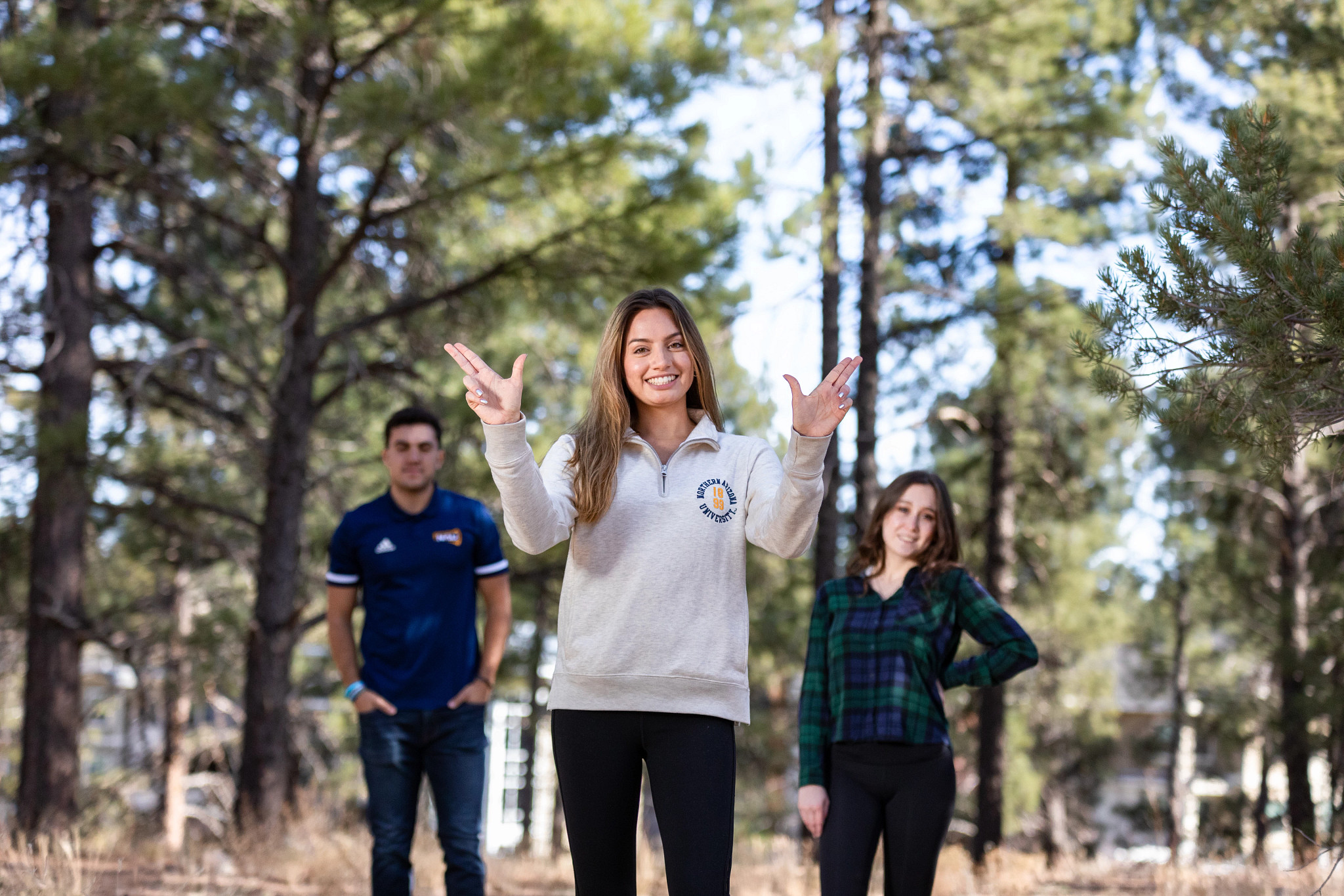 Student pose for a picture in the forest and using Jack's hand signal.