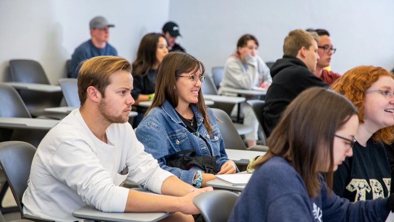 A photo of students listening to a teacher in class.