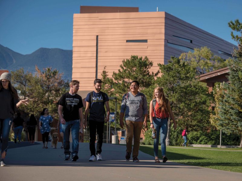 Four students smiling while walking together outside.