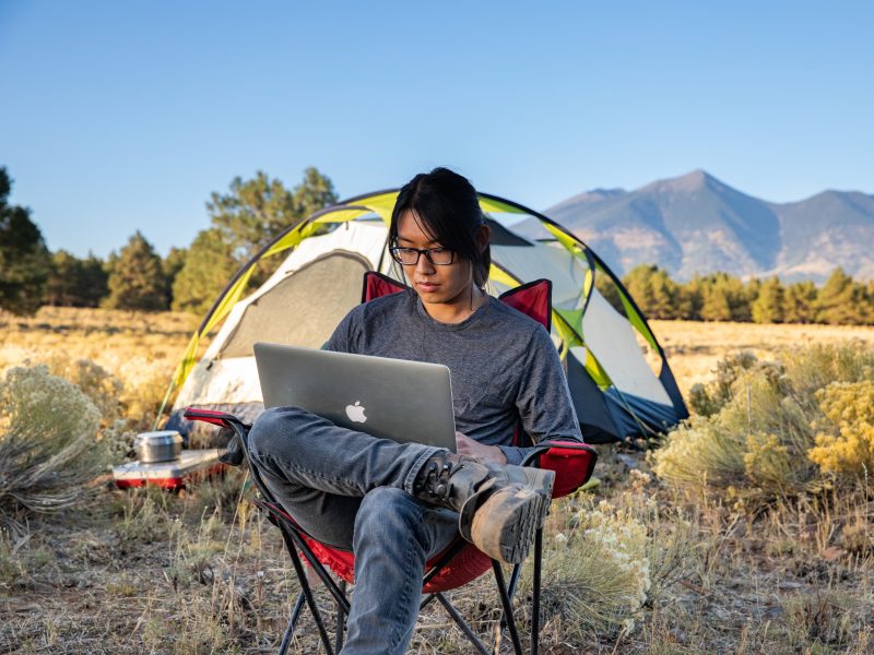Student looks at laptop while sitting outside.