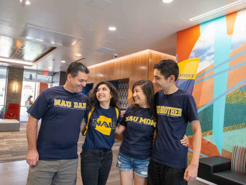 A photo of a family dressed in N A U attire proudly supporting their freshman.