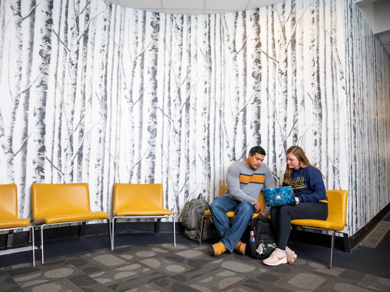 Professor reviewing student's work in a lobby.
