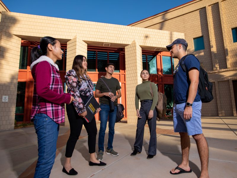 A group of students stand outside and chat.