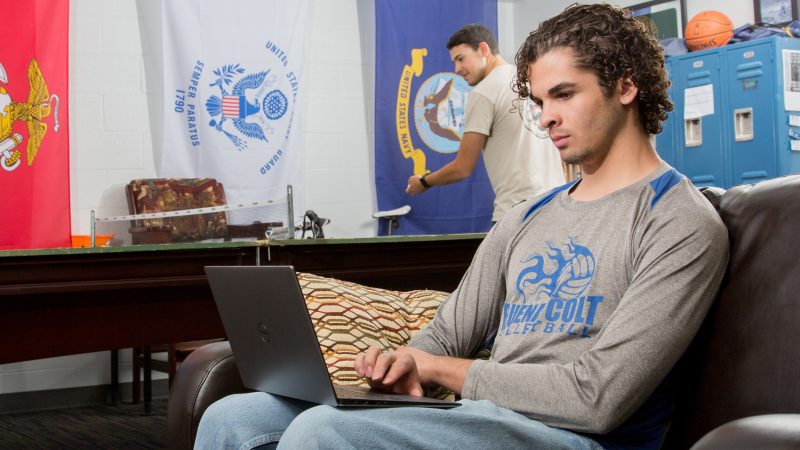 A student sitting and using a laptop in the veterans center.