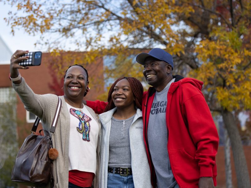 A student and family smiling and taking a photo.