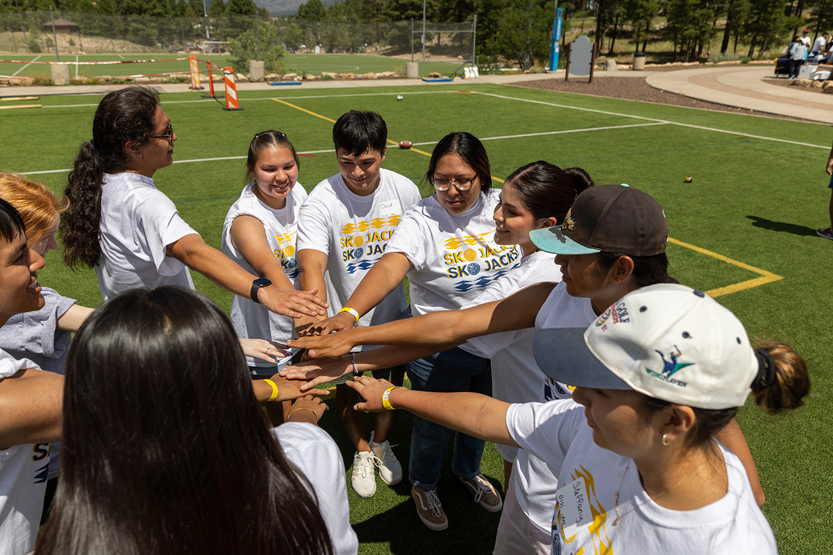 Indigenous students wearing S K O Jacks shirts gather on the soccer field.