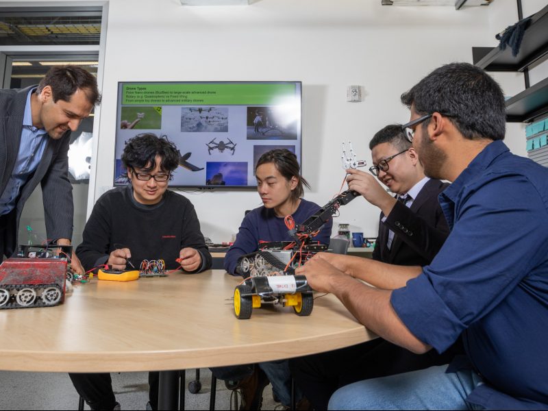 Student researchers inspecting robot.