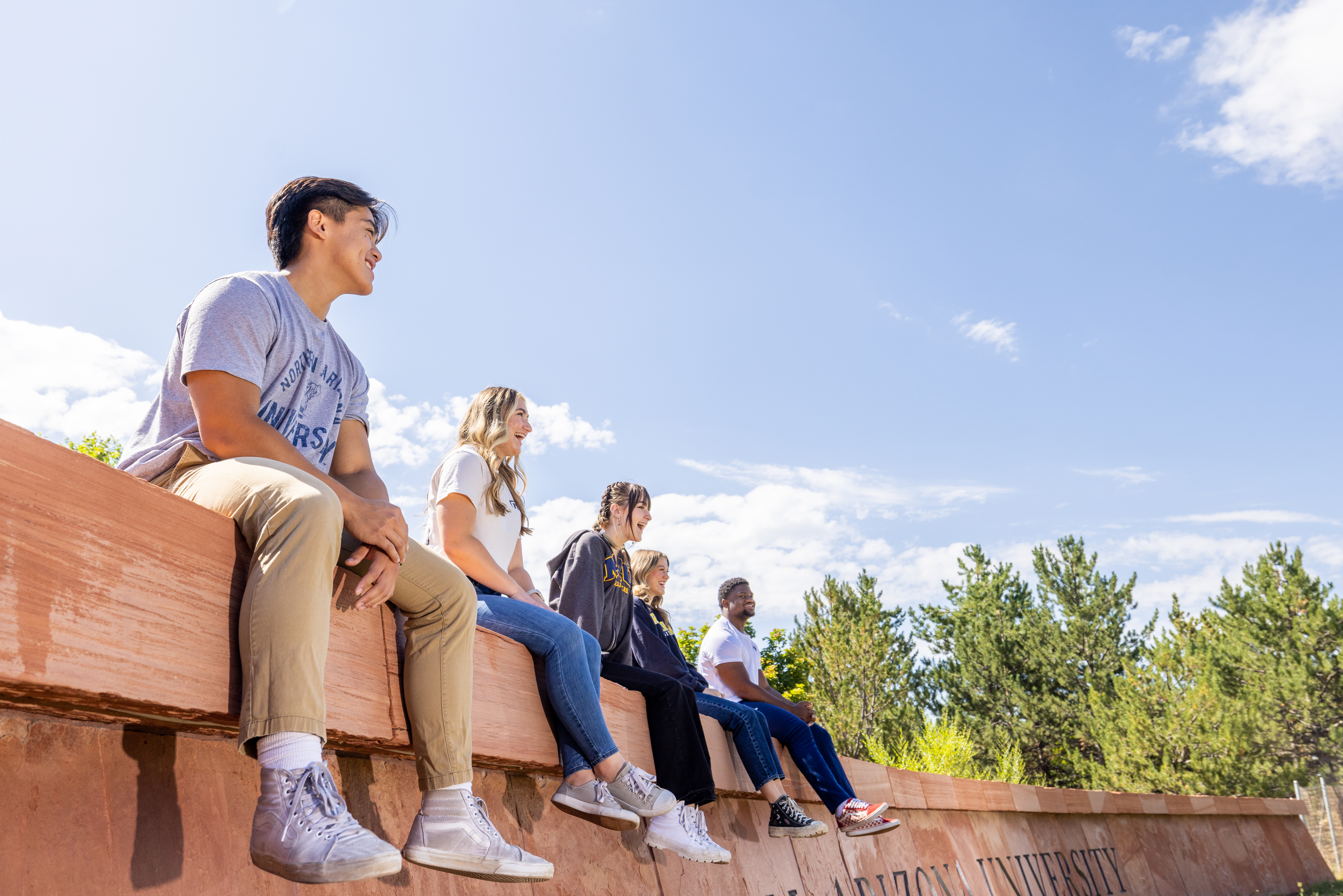 A photo of students sitting on the N A U sign.