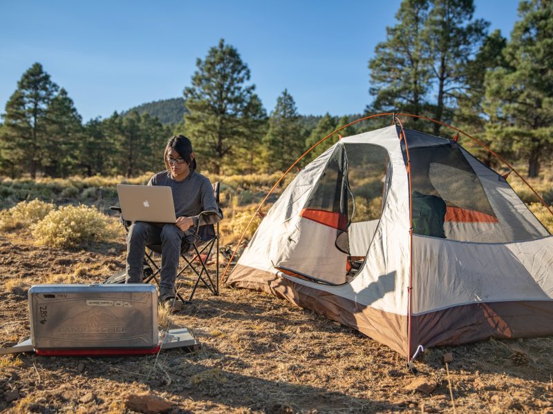A photo of a student outdoors next to a tent.