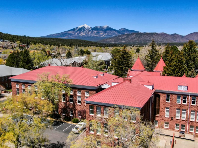 A drone photo of N A U Flagstaff campus with mountains in the background.