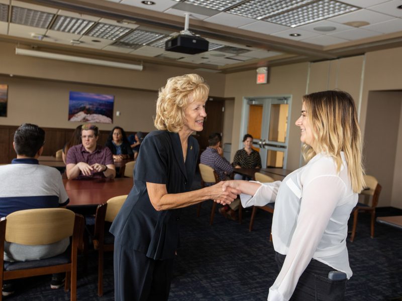An N A U alum shaking hands with a current student.