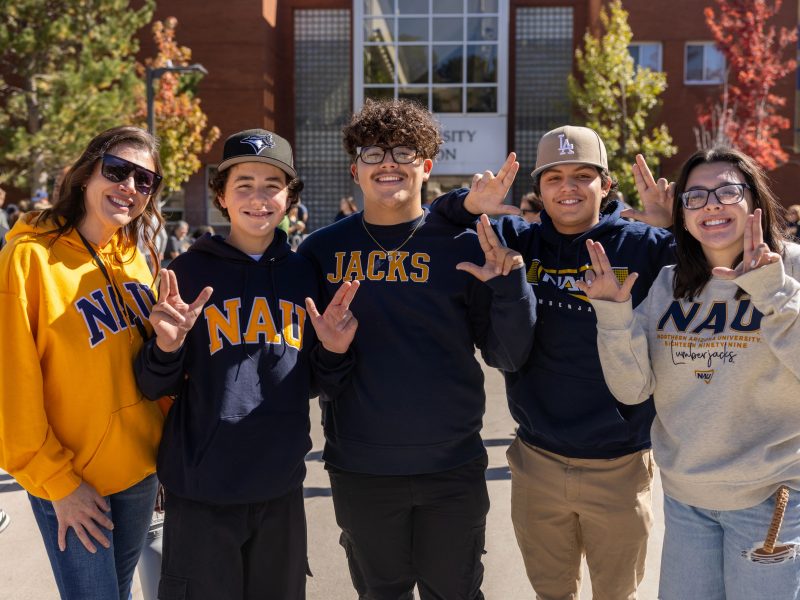 N A U students smiling at camera outdoors.