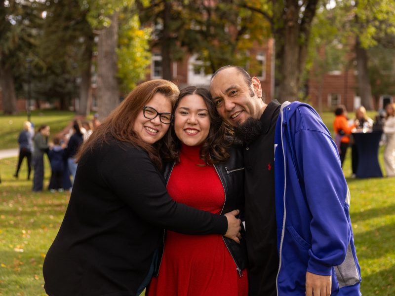 Student smiling with family outdoors.
