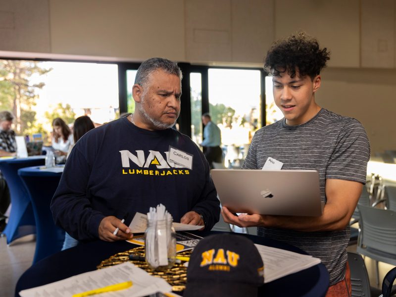 Student speaking to a faculty member with a laptop.
