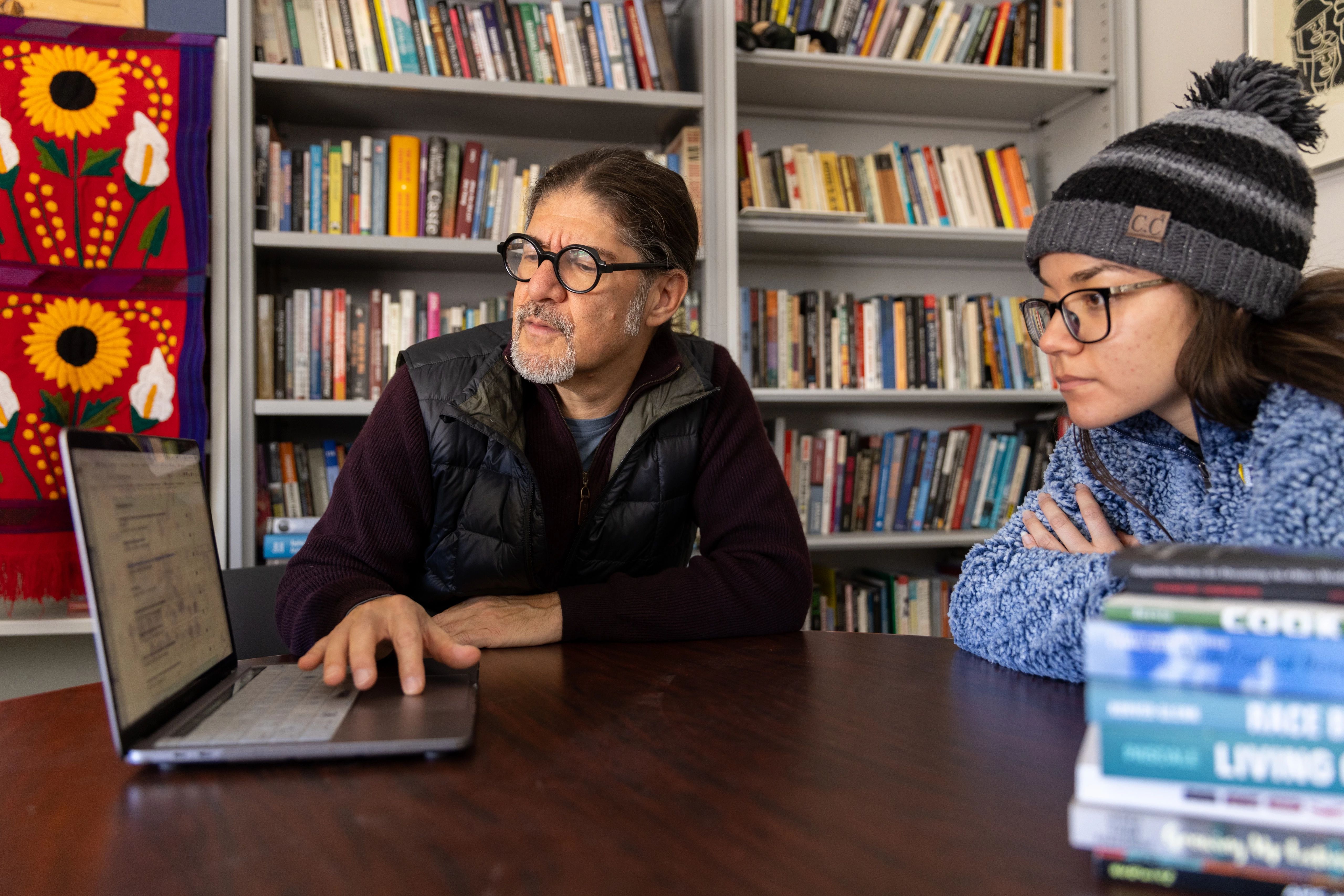 Student looking at laptop with a faculty memeber.