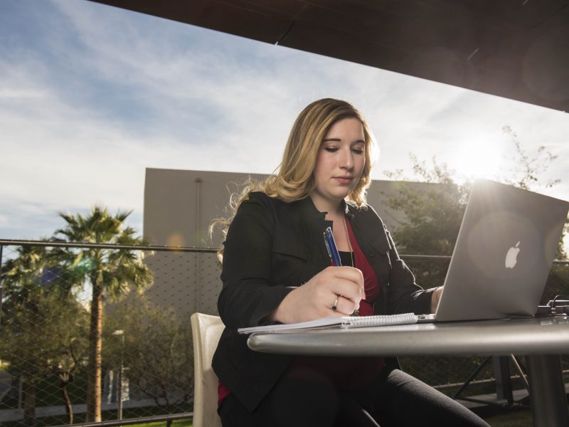 Faculty using laptop outdoors.