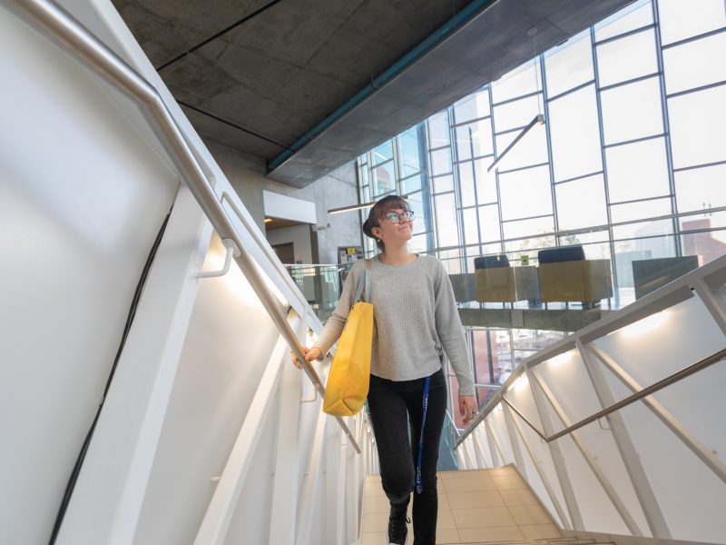 Student climbing stairs inside campus building.