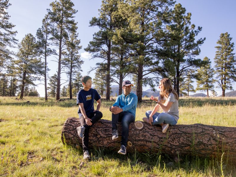 N A U students sit on a fallen tree trunk at Buffalo Park in Flagstaff, Arizona.