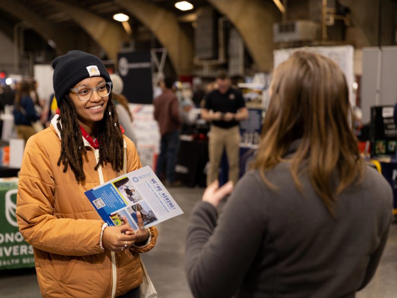 A student talks to a coordinator at a career fair.