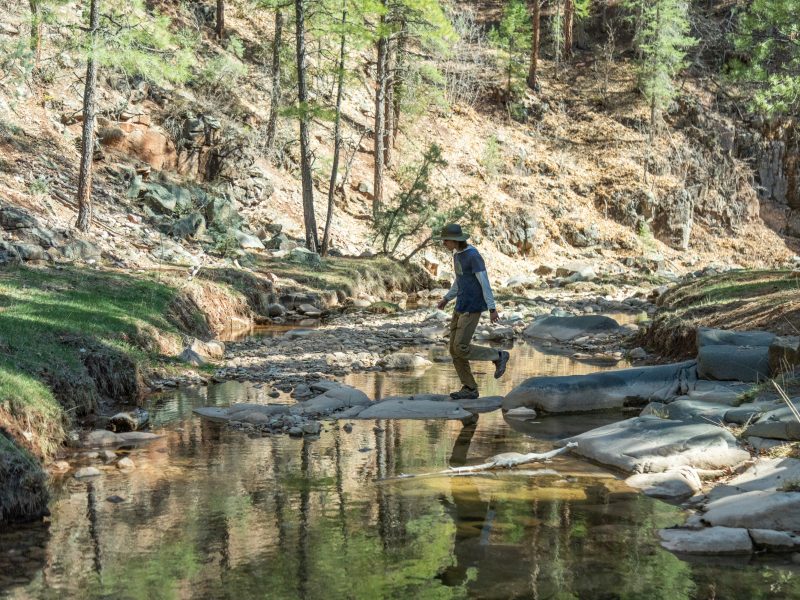 Student walking on rocks across a creek.