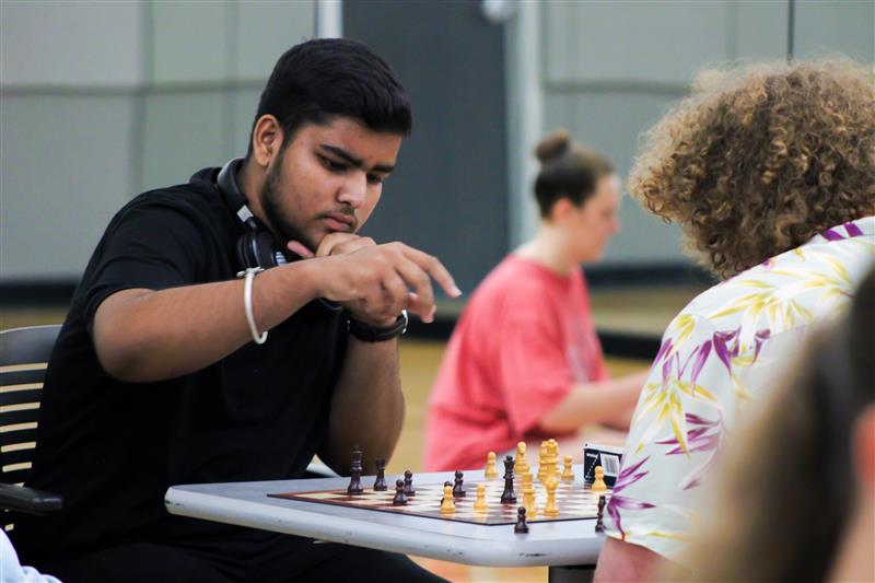 Two students are sitting at a table playing chess.