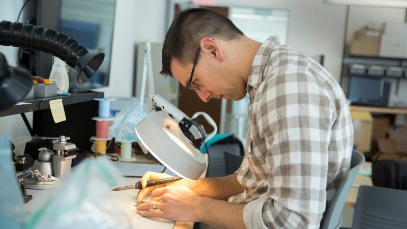 Student working on soldering an object.