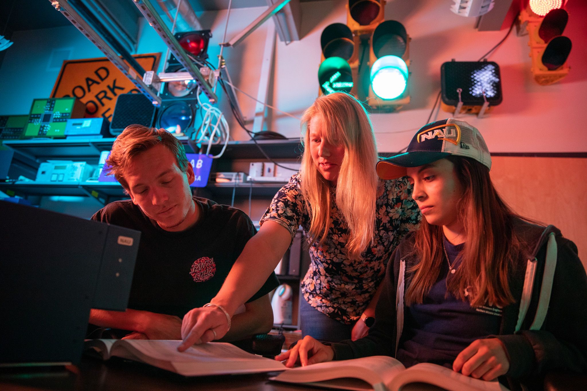 Professor helps two students with reading assignment.