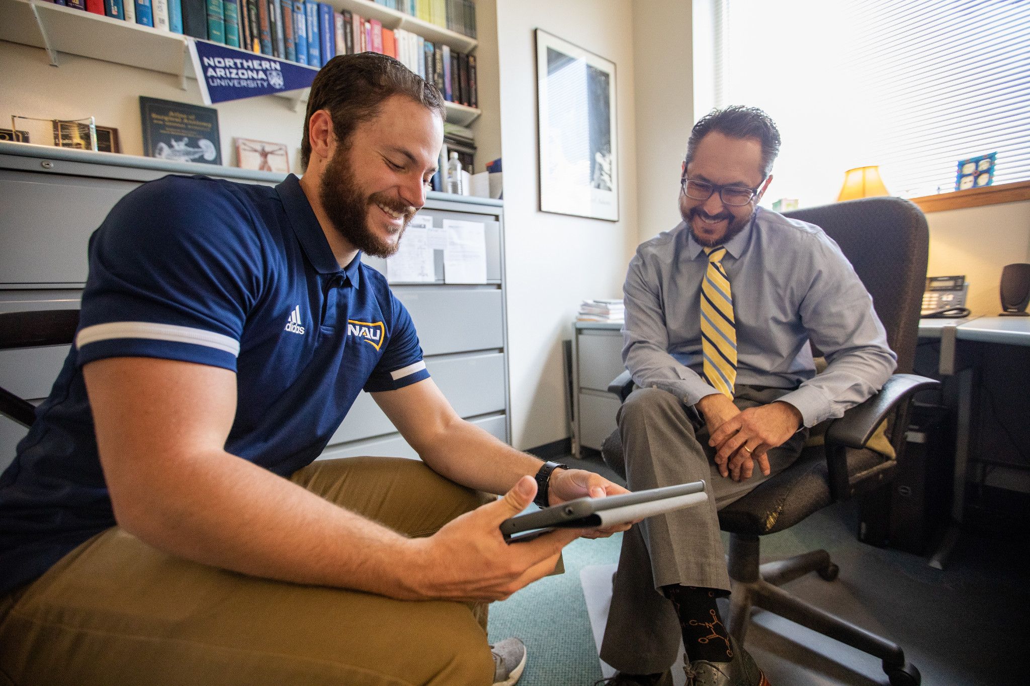 Two N A U associates are looking at a iPad together.