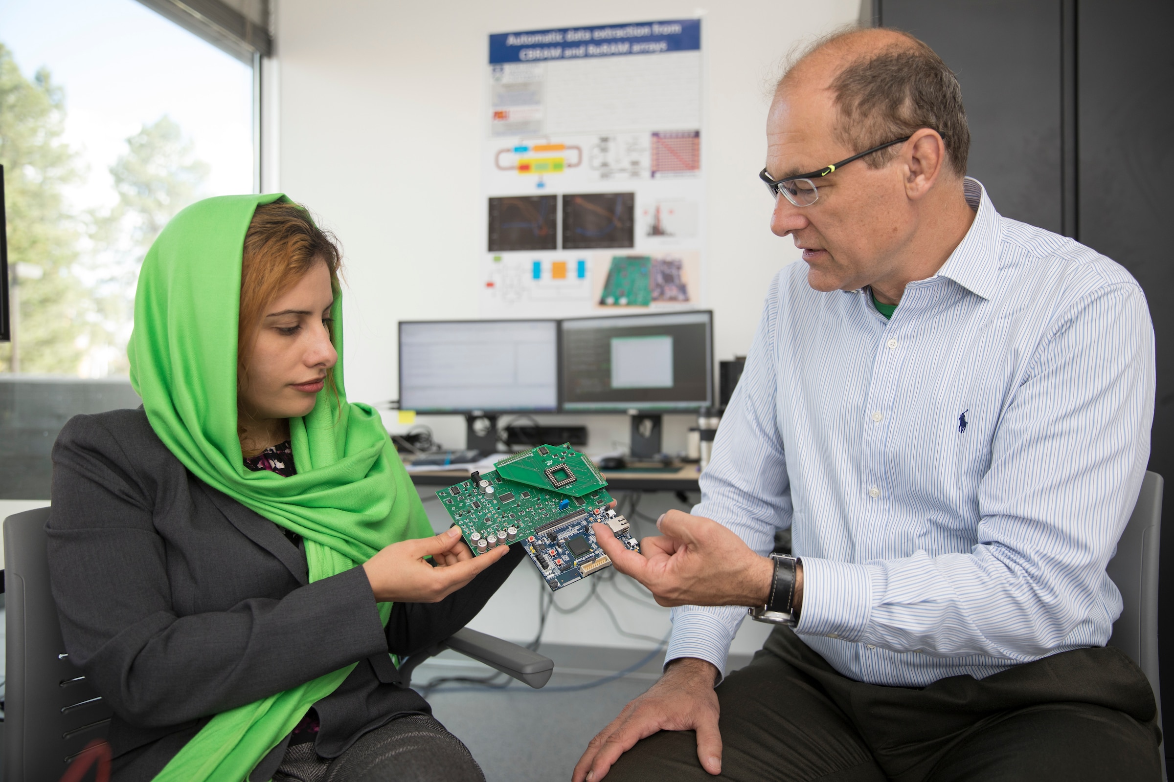 Student and professor are holding and looking at circuit board.