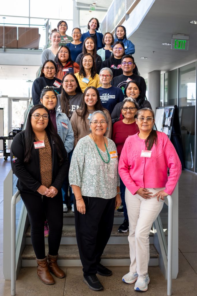 A group image of 21 women of varying backgrounds standing on steps smiling